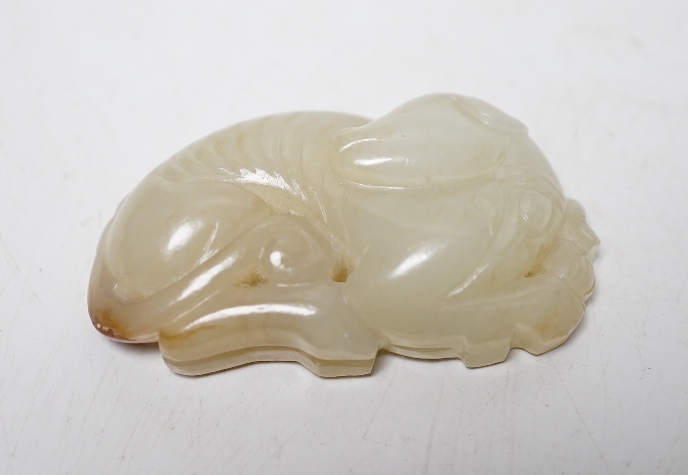 A Chinese pale celadon jade hound plaque, 5.2 cm